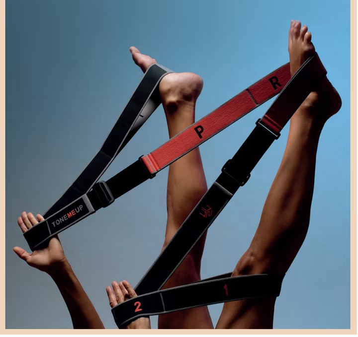 Legs raised using a TONEMEUP stretching strap against a blue background