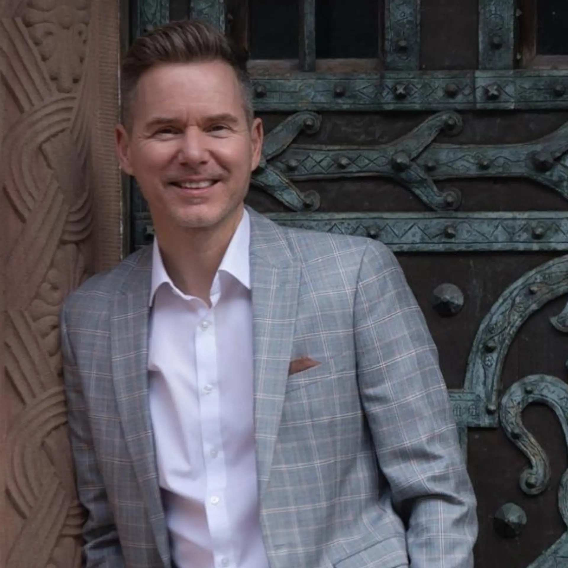 Holger Nitsche smiling, leaning against an ornate doorway